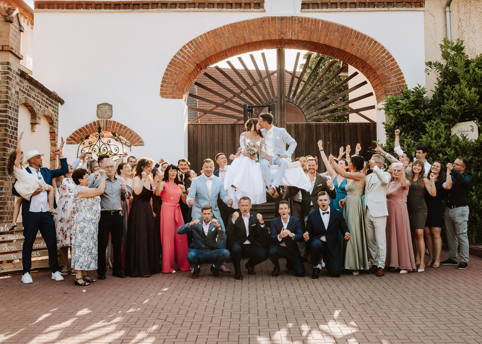Brautpaar mit Familie beim fröhlichen Gruppenfoto mit Hochzeitsfotograf in Leipzig